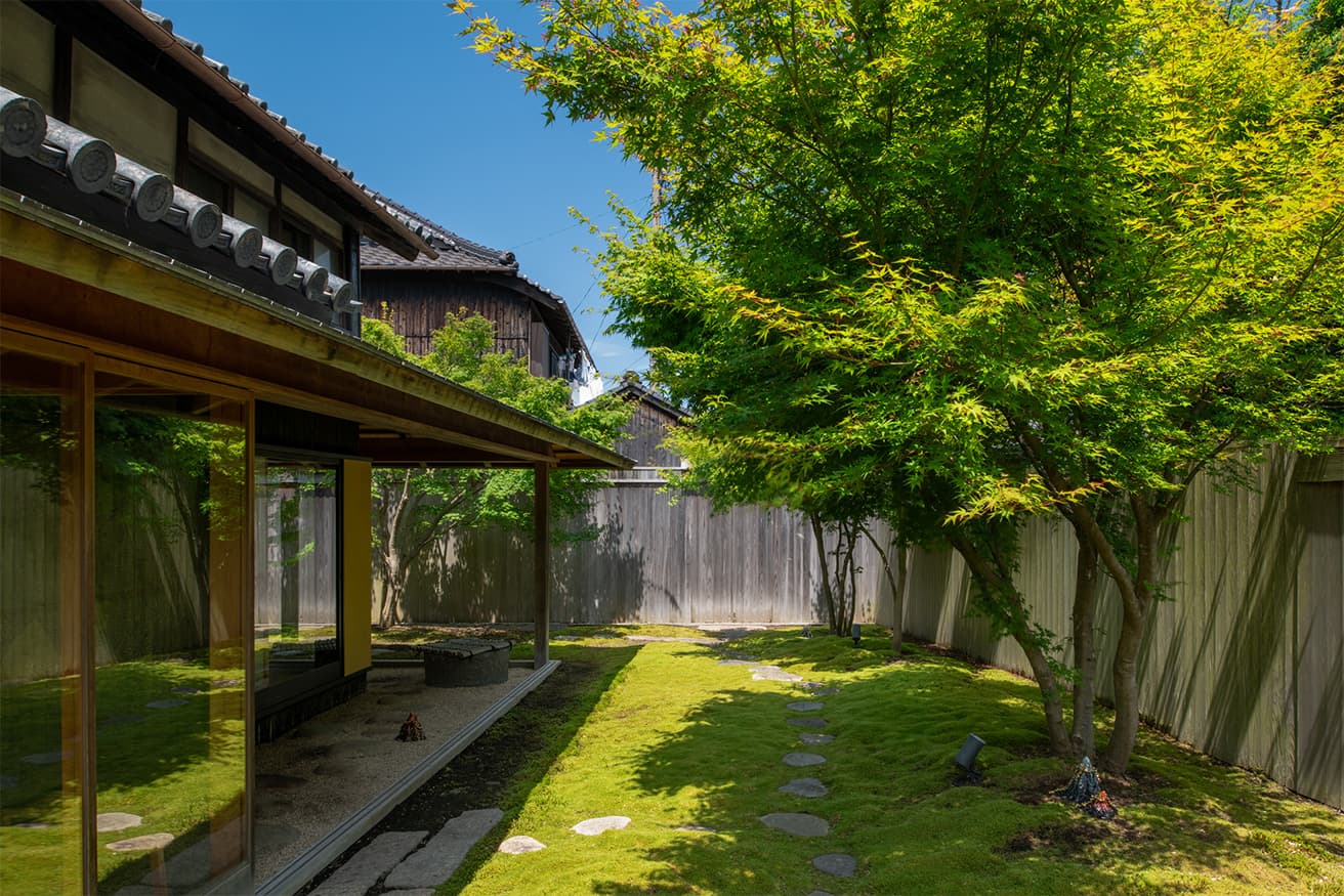 直島の本村地区に位置する〈またべえ〉の母屋と苔庭。築100年以上の民家で、この地区の特徴である「南北に抜ける続きの間、縁側、庭」へと戻し、接客の空間として2016年に三分一博志が改修。隣に増築した離れがある。photo_Nobutada OMOTE