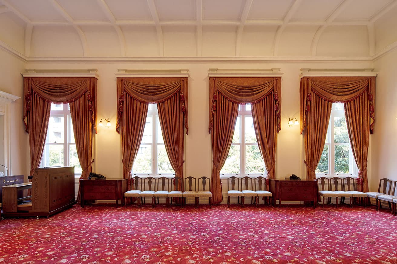 2階東側ホール。洋風のインテリアながら天井を和風の折上格天井としており、これは能舞台（ステージ）を設けていたことによる。