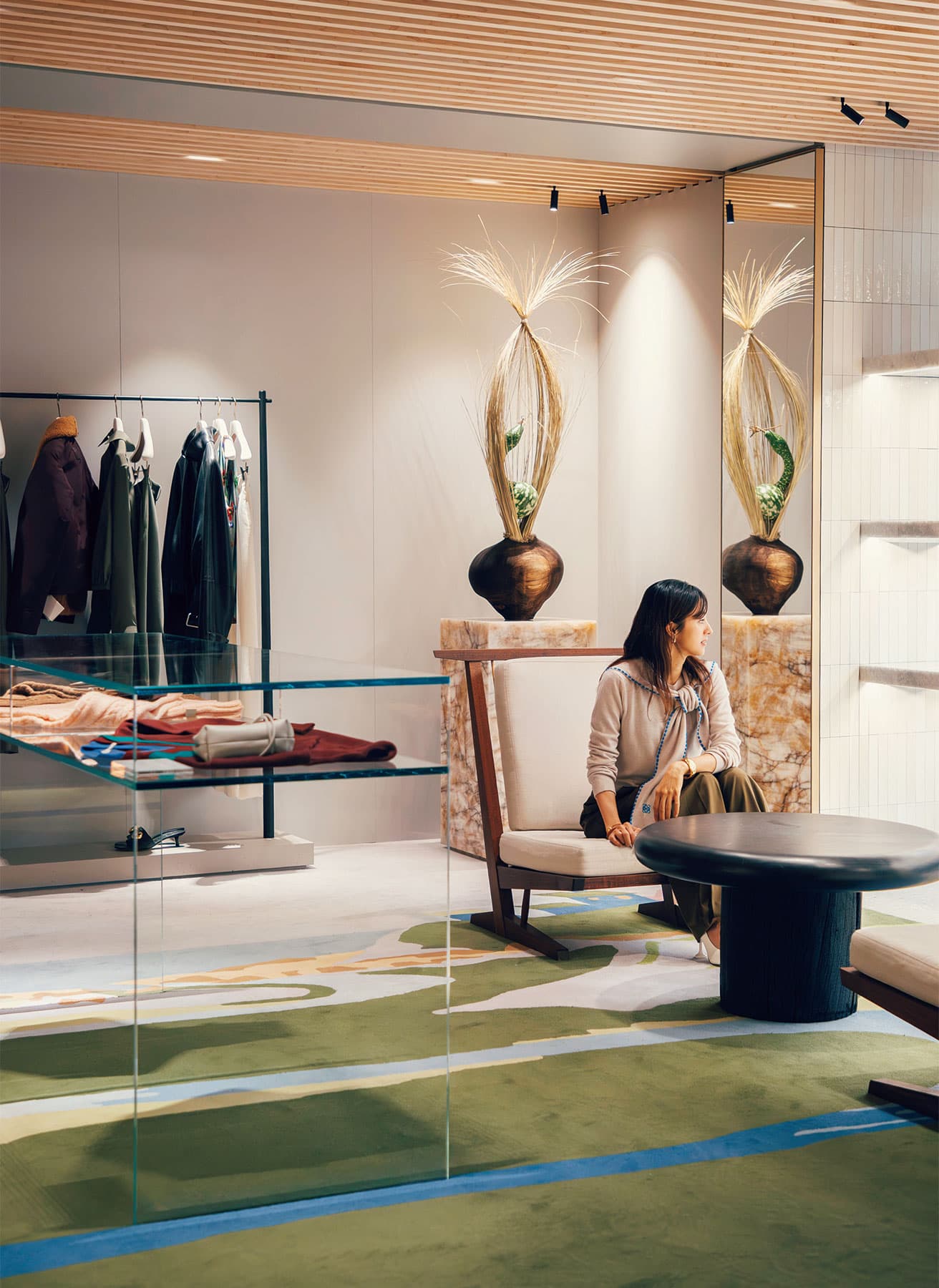 〈ロエベ〉独自のブラックテラゾーで作られた丸みのあるコーヒーテーブルや英国のテキスタイルアーティスト、ジョン・アレンが手がけた鮮やかな風景を再現したスペイン製のオーダーメイドラグ。アートコレクターの邸宅のような親密さのある2階の空間。