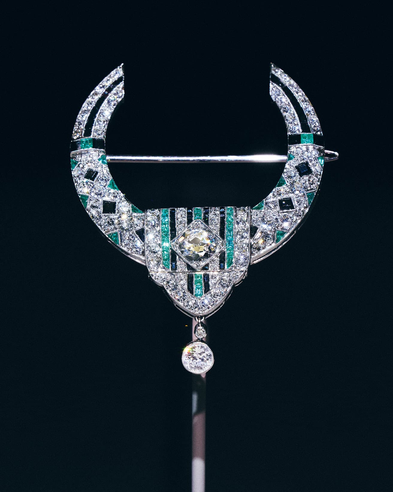 《ループ ブローチ》1919年、プラチナ、エメラルド、オニキス、ダイヤモンド。〈ヴァン クリーフ＆アーペル〉の歴史においてアール・デコ様式の萌芽といえる作品。扉や窓を縁取る布製の垂れ飾りの形状を反映させたデザイン。