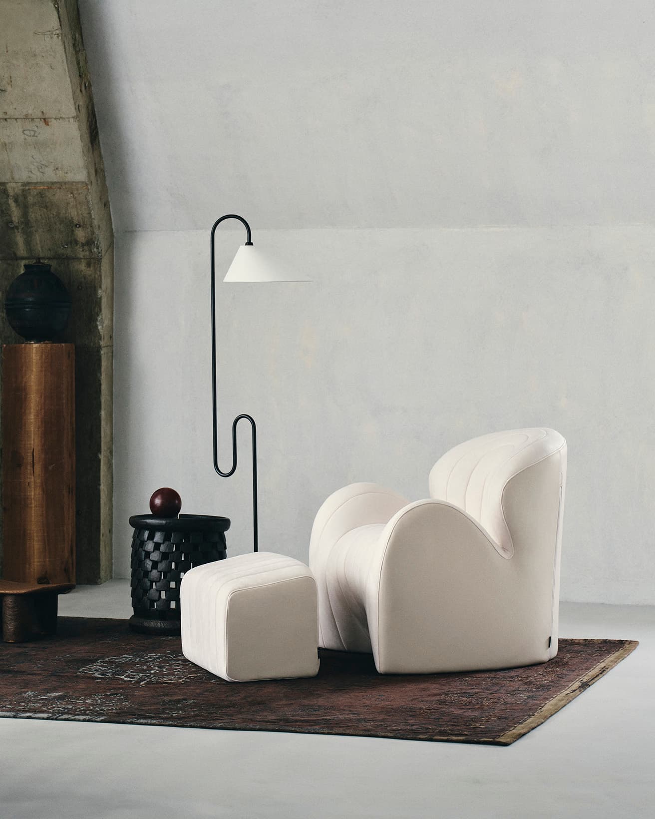 《Style Sofa WL（One-Seater）》W73×D80×H75cm 132,000円。《Style Sofa WL（Ottoman）》W51.5×D34.5×H36cm 33,000円。ベルギー製のメダリオン柄の平織りラグ《フェーディングワールド》200×280cm 248,600円（オルビテックス https://orbitex.jp/ ）。〈クラシコン〉のフロアランプ《ロアッティーノ》W68×H151cm、ベースφ21cm 663,300円（マーケット https://maarket.jp/ ）。カメルーン・バミレケ族の木製スツールφ37×H41cm 132,000円、マリ・バンバラ族のフタ付素焼き壺φ26×H36cm 132,000円（ともにギャラリーかんかん 本店 TEL 03 5486 3122）。その他スタイリスト私物。