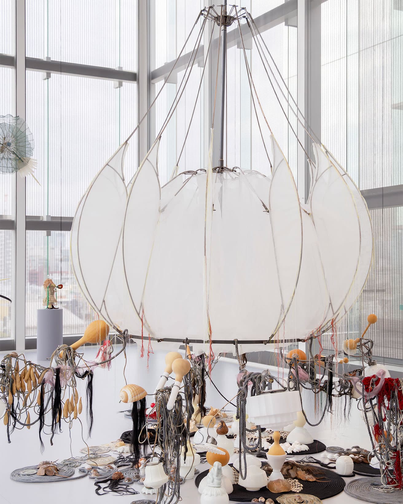 《Black Noodles》2023年。白い布を張った巨大なランプシェードのような作品には人毛が使われている。インドは世界の人毛取引の主要地とのこと。そのほか照明器具のシェードやひょうたん、綿の紐などが複雑に組み合わされている。