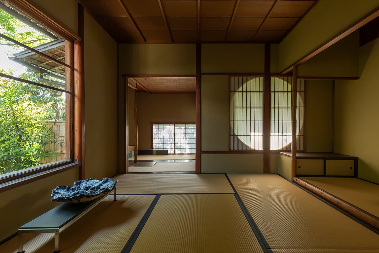 寝室の丸窓は庭の眺めを楽しめるよう、窓の桟を独自の割り付けとしている。ポール・ケアホルムのテーブルには星野曉《Spring Snow 22-P9》 。