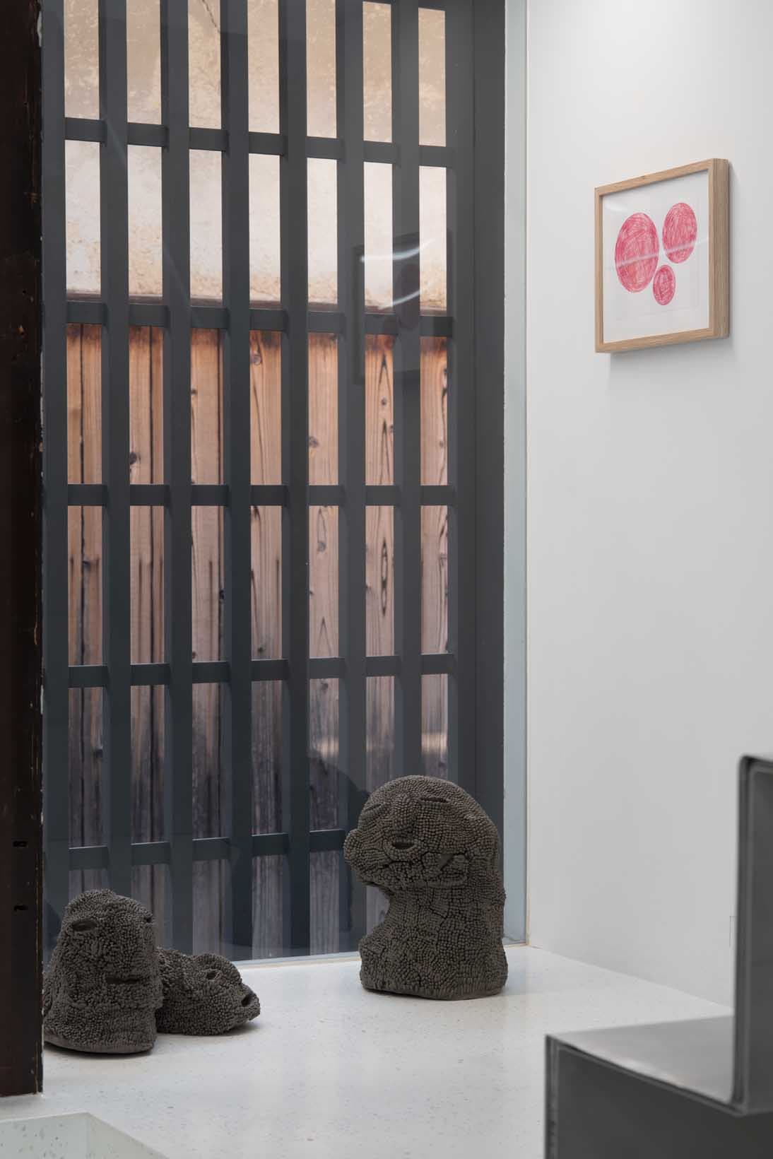 ギャラリーの一角に飾られた鎌江⼀美の立体作品。彼女の作品はすべて「まさとさん」との恋物語がベースになっており、写真右は《新婚旅⾏でフランスへ⾏く私とまさとさん》（2022年）。壁にかかるのはボールペンで描かれた⼩川翔陽の作品で、タイトルは不明。
