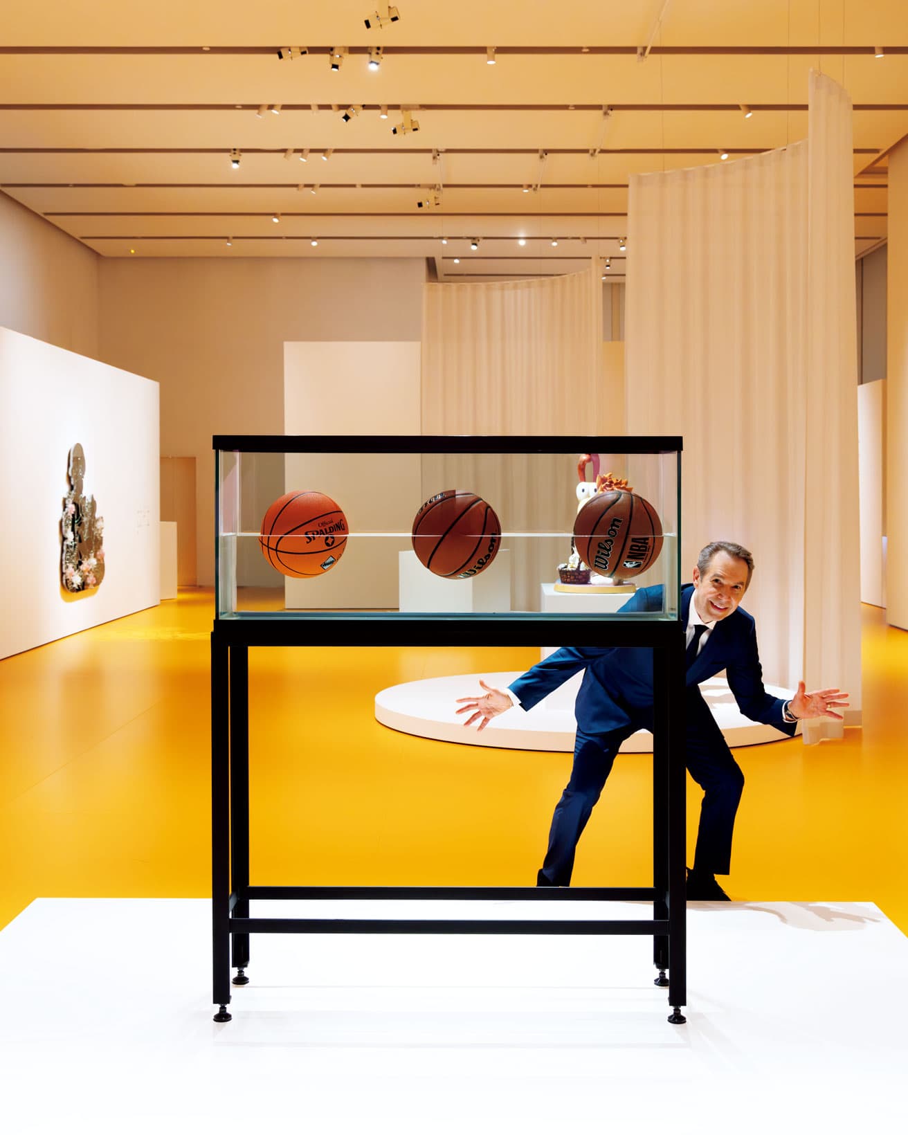 《スリーボール・50/50・タンク（ウィルソン NBA フォージ・プロ、ウィルソン NCAA アンコール、スポルディング Dr. JK シルバー・シリーズ）Three Ball 50/50 Tank(Wilson NBA Forge Pro, Wilson NCAA Encore,Spalding Dr. JK Silver Series) 》（1985）。1980年代にクーンズの名声を飛躍的に高めた「Equilibrium（平衡）」シリーズの一作。水槽の中の３つのバスケットボールは中心線が水面に来る状態で浮遊している。わずかずつ動いたり沈んだりするのを修正し続ける必要があるその様が〝永遠〞の概念を問いかける。