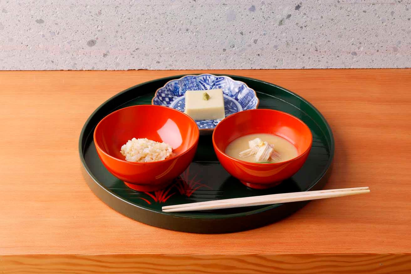 折敷に載せた飯、汁、向付で始まる茶懐石スタイルを踏襲。この日の汁は結び生麩、芹に溶き辛子を添えて。飯は金沢市近隣の能美市産のミルキークインの玄米ごはん。向付はうすい豆の胡麻豆腐。
