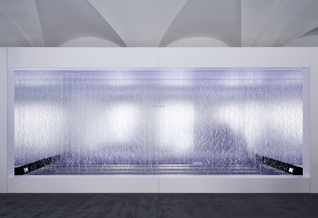 進藤篤による《PULSE OF TIME》の展示風景。幾重にも連なる透明な波打つ線状に光が乱反射。時間の経過によって刻々と変化する表情をじっと見ていると、意識がどんどん小宇宙の奥へと引き込まれていく。