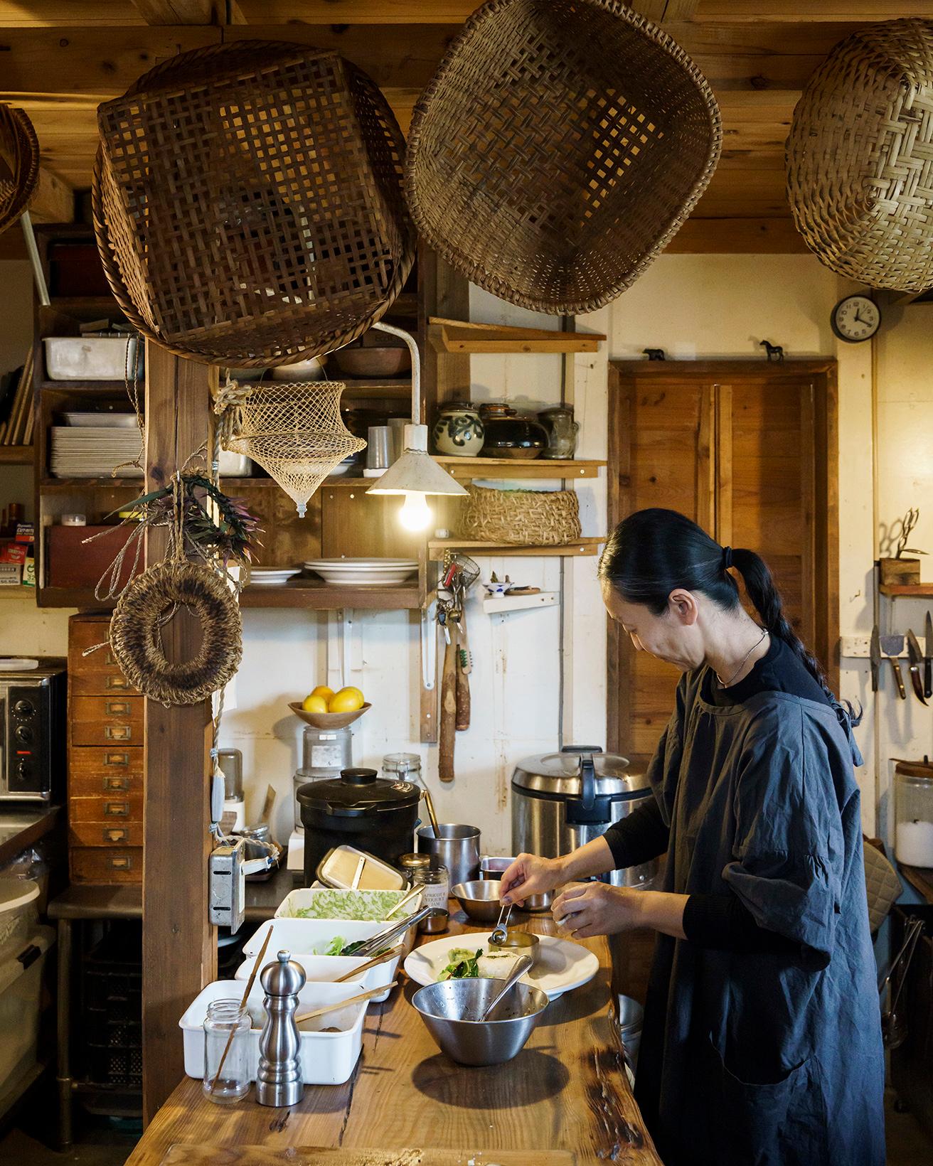 キッチンで調理中の根本きこさん。近著は『沖縄 今帰仁「波羅蜜」の料理、カレー、ときどき水餃子』（KADOKAWA刊）。常時カレーや餃子の提供はないが、第3水曜の夜は「水餃子の日」（要予約）を開催。