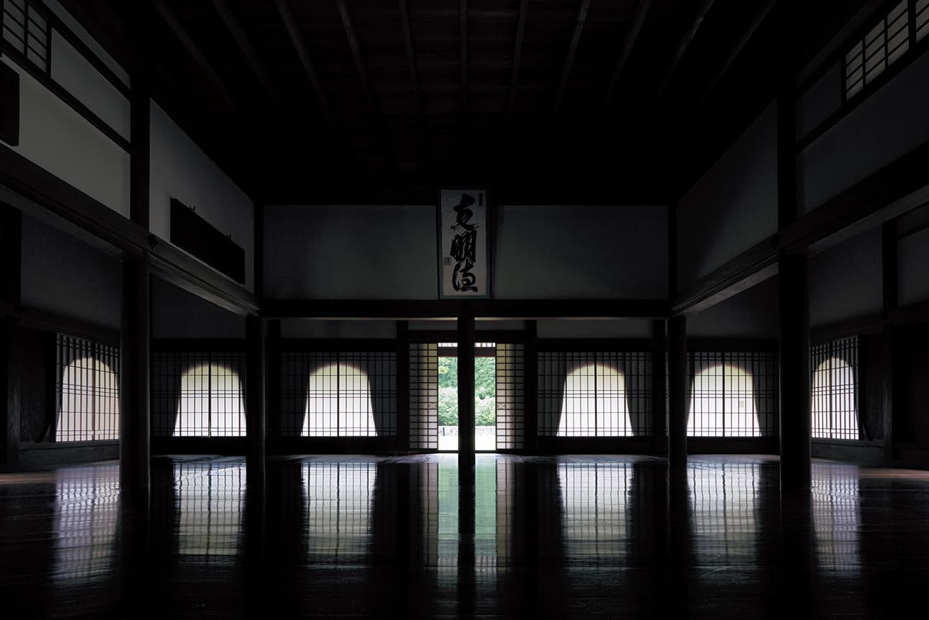 閑谷学校の講堂。中央の空間を囲む10本の円柱は直径25cm以上の欅(欅)の木で作られている。正面にある「克明徳」の書は5代藩主・池田治政によるもの。