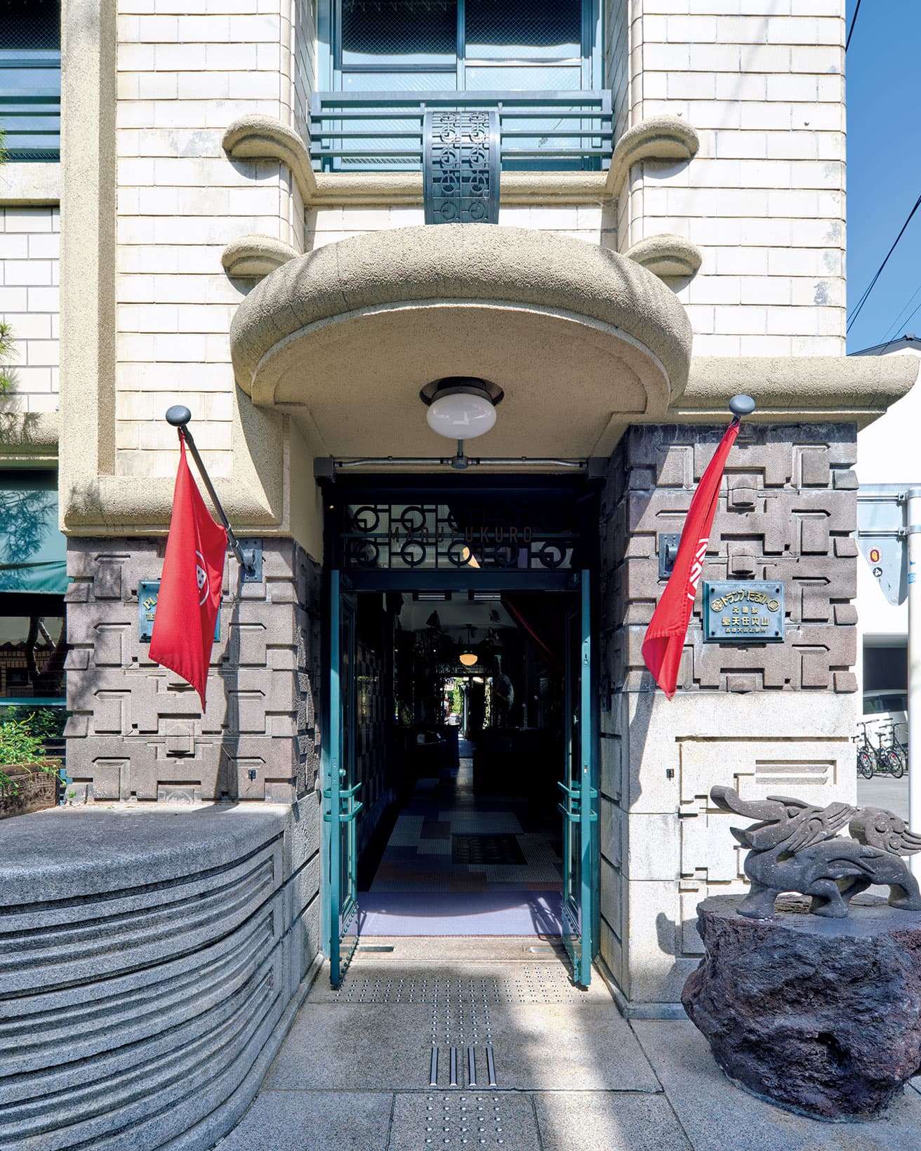 南端の旧事務所棟の正面玄関右手に当時のままの社名板が残る。