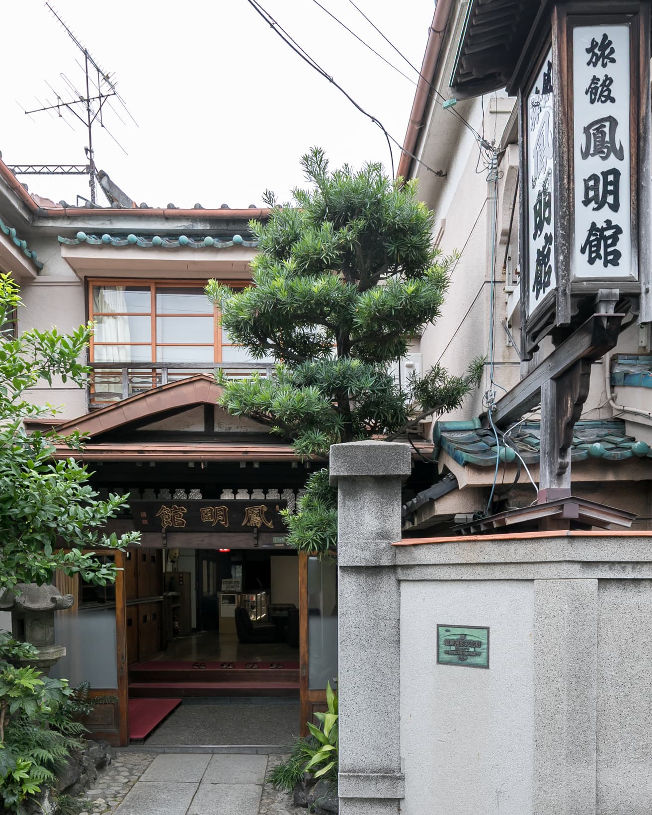 「鳳明館」の看板にも注目を。入口の木製の看板は「明」の字が“窓”を表す特別な書体が用いられている。外の縦長看板は、鳳凰が翼を広げたように「鳳」の字が躍動的な書体。